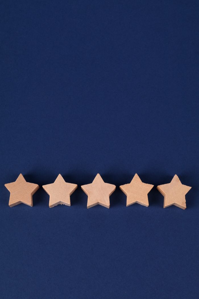 Five wooden stars lined up on a blue background, symbolizing a rating or quality concept.